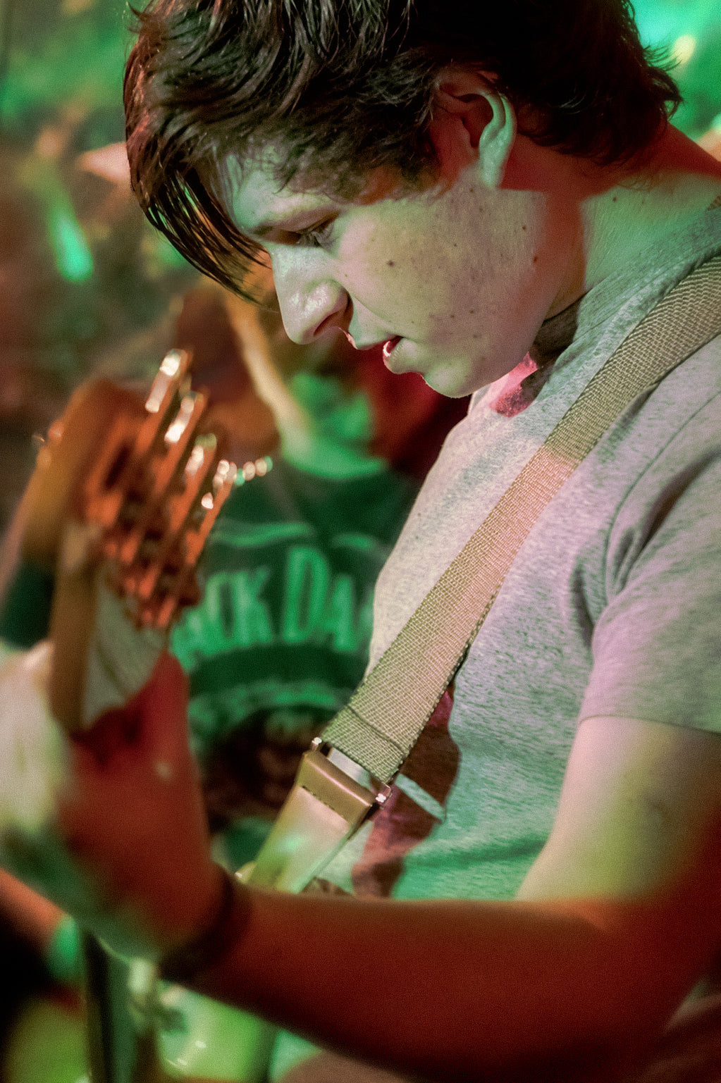 Atmospheric live music photography capturing a guitarist performing on stage beneath dramatic green and red lighting. The image focuses on the intensity, movement and emotion of a live performance, making it ideal for music, band, event, editorial and creative photography content.